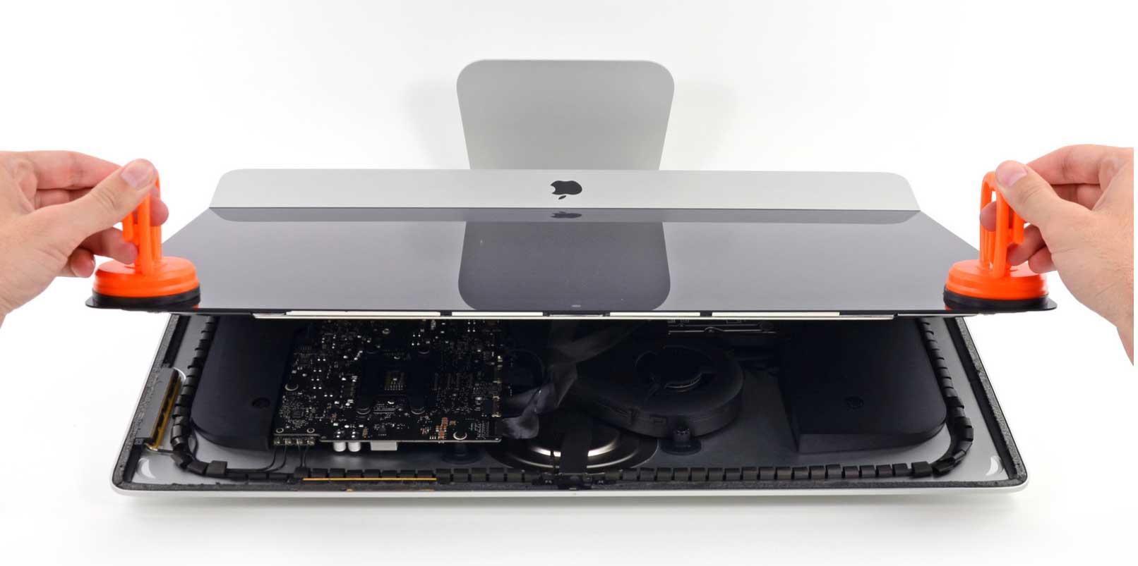 Technician opening an iMac display for component-level internal repair — logic board, cooling, and power modules exposed
